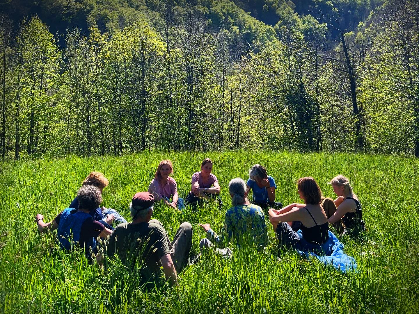 A group sitting together in the meadow below the house