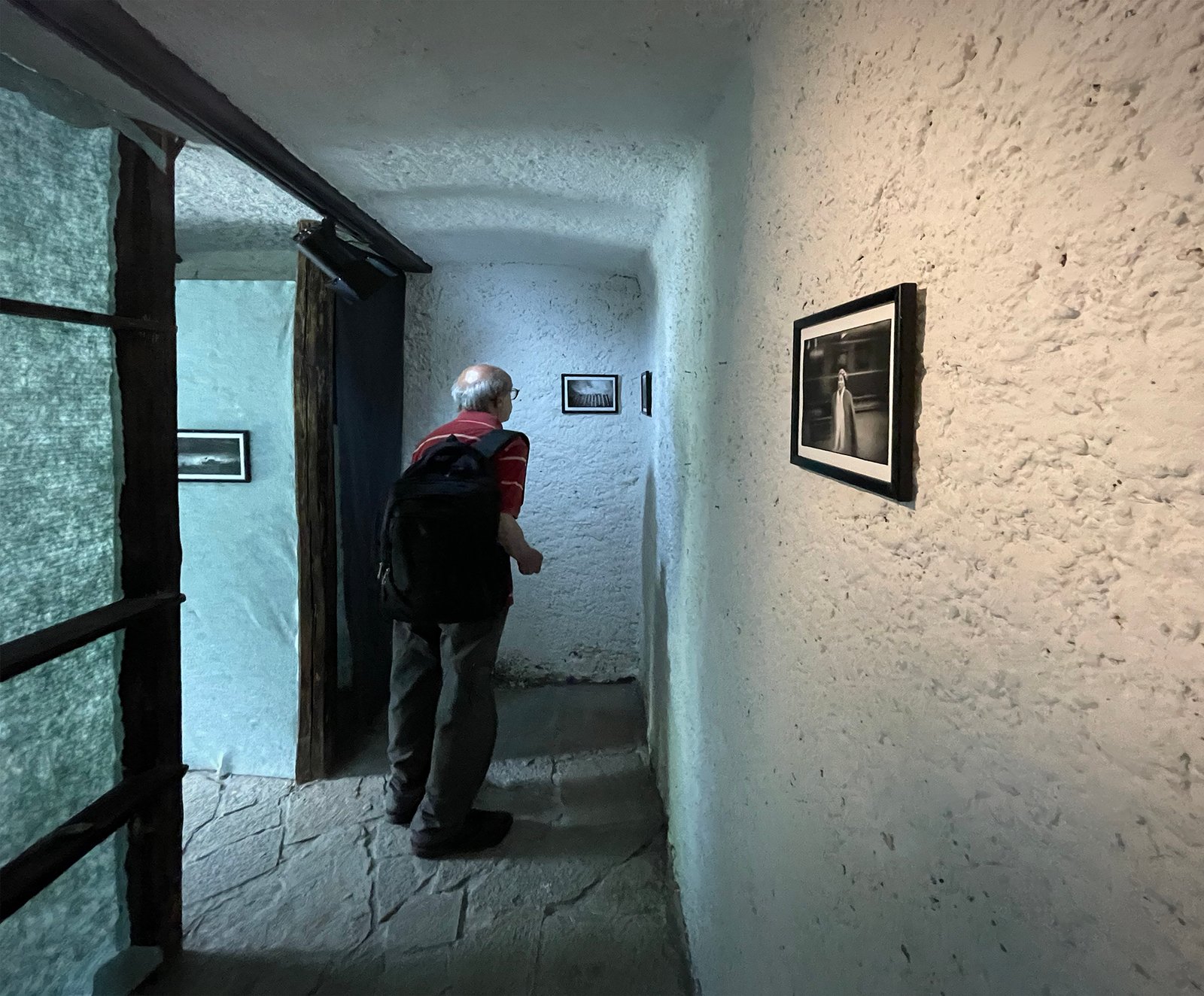 A visitor looking at photographs in a stone-walled gallery