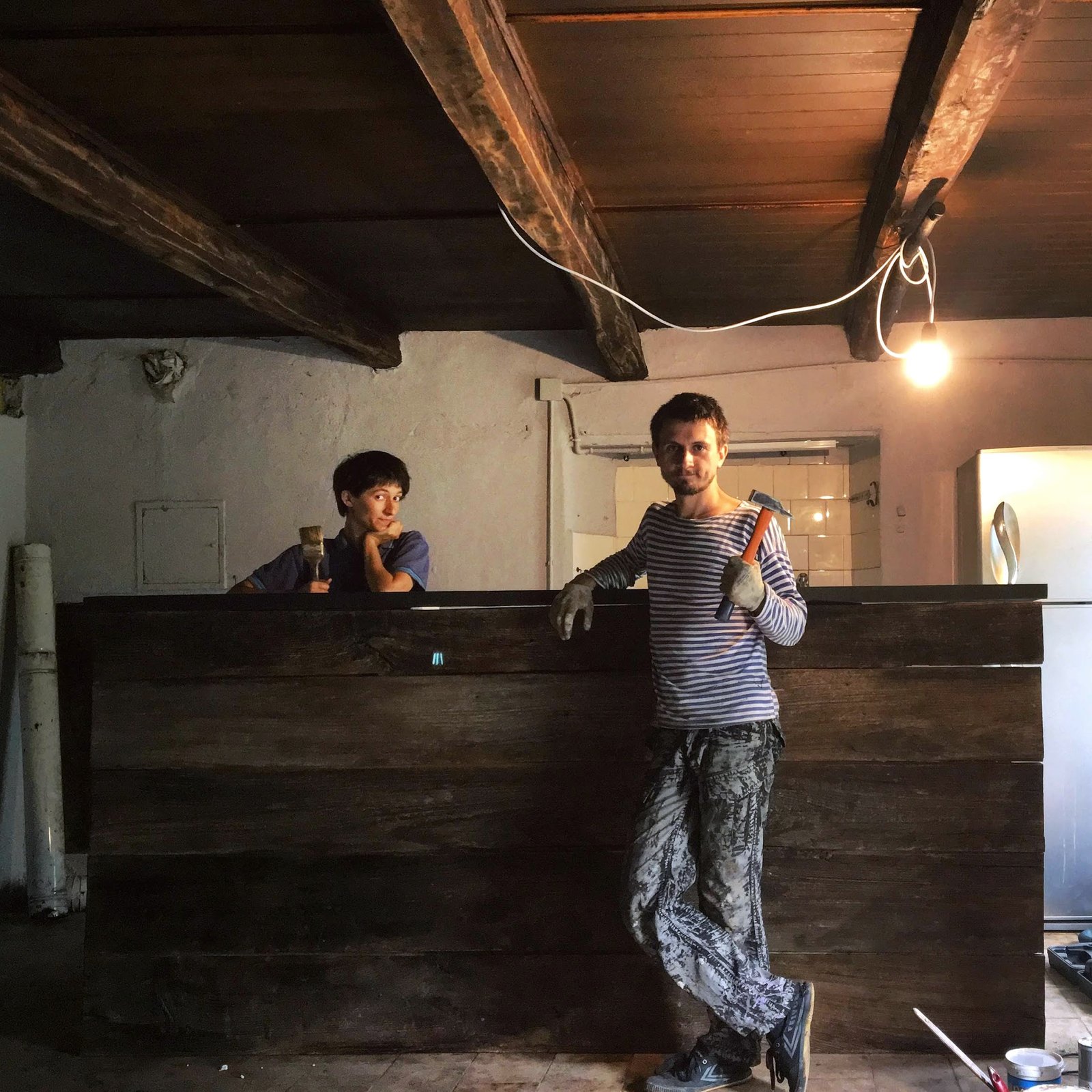 Two people working on a wooden partition during restoration