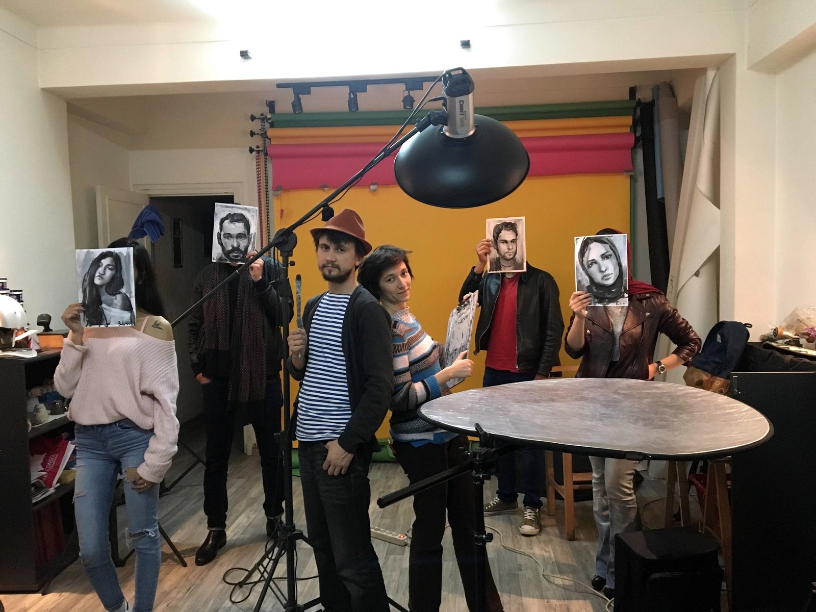 A group in a studio holding their painted portraits